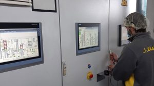Operario elecpor abriendo puerta de cuadro de automatismos industriales