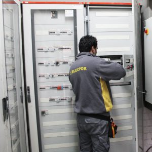 Operario de elecpor realizando tareas de mantenimiento en cuadro industrial eléctrico