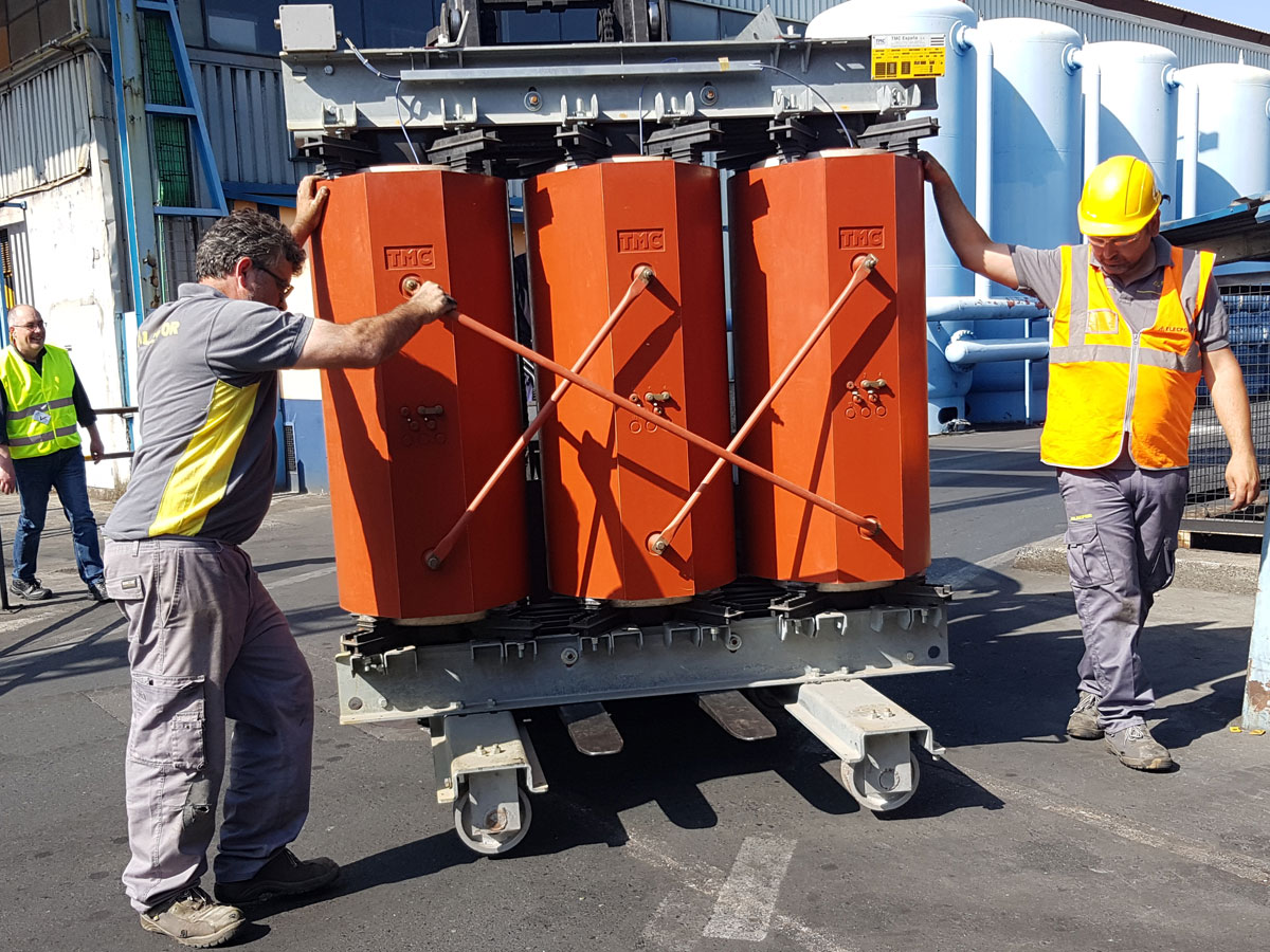 Operarios de elecpor transportando equipos de transformación